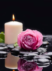 Pink rose with white candle and therapy stones 