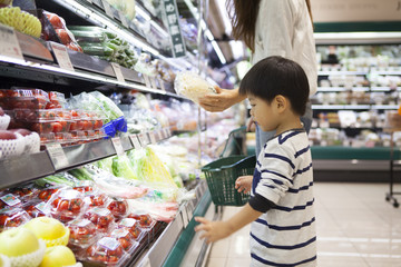 Mother and son are choosing vegetables in the supermarket