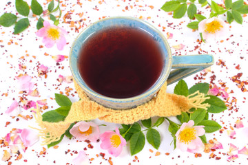 Cup of tea with wild rose flower on white background