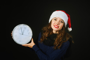 Cheerful beautiful young woman in hat of Santa Claus shows Christmas time