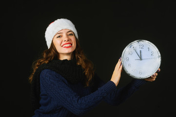 Cheerful beautiful young woman in hat of Santa Claus shows Christmas time