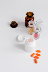 colored pills in glass bottles on white background