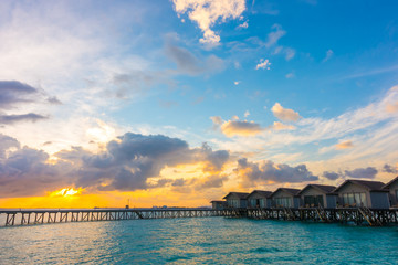 Obraz premium Beautiful sunrise with water villas in tropical Maldives islan