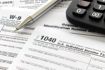 US tax form with pen and calculator, over light [blur and select focus background]