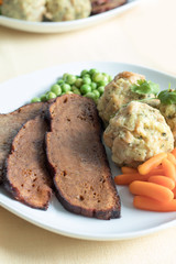 Seitan steak with bread dumplings and fresh peas and baby carrots