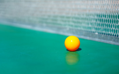 details of pingpong table with playing equipment and yellow ball.