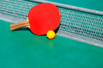 details of pingpong table with playing equipment and yellow ball.