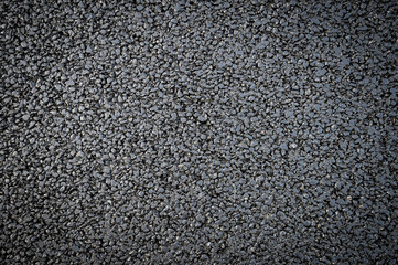 Fresh black asphalt in a textured close-up full frame background 