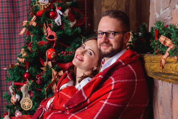 Happy brunette bride and gorgeous groom in the cozy plaid. Christmas tree. - 125796019