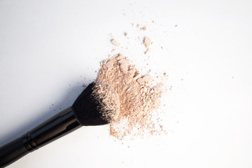 black cosmetic brush and puff-box of powder on a white background 