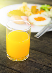 glass of orange juice and breakfast meal with soft sun light effect