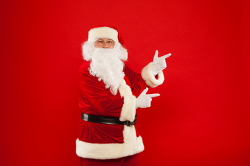 Santa Claus pointing in blank a place, red background