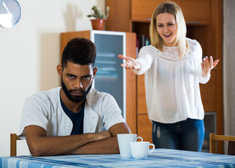 Blonde girl yelling at black boyfriend as quarreling indoors