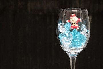 Still life Photography with Santa Claus in a glass of wine with ice in night time with dark background,