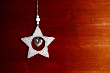 weisser Weihnachtsstern aus Holz vor roter Holzwand