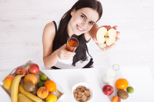 Beautiful women exists with pure skin on her face sitting at table and eat breakfast. Asian woman eating healthy food at breakfast. Fruit, cereal and milk. Unusual view, top view, selective focus