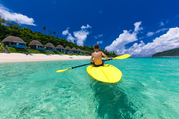 Young shirtless caucasian boy kayaking at tropical sea on a kaya