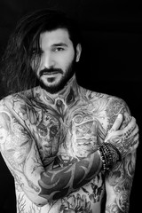 Tattooed naked man on black background