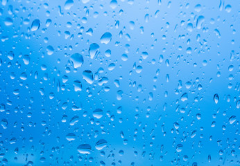 Raindrops on glass with blue light background, Drops of rain on blue glass 