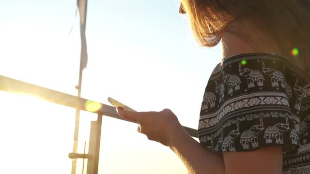 Young girl on the beach with your smartphone. Sunset