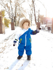 baby boy in warm snowsuit walking winter park