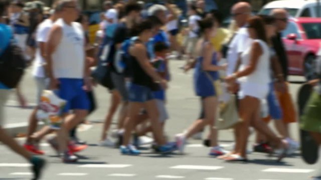 Side view blurred pedestrians crossing a street in the city of Barcelona in summer.