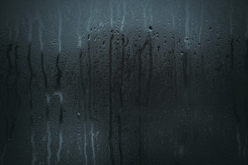 Flowing down water drops on glass