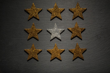 Fototapeta na wymiar Silberner Stern zwischen goldenen auf Schiefer Untergrund
