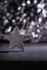 Fototapeta na wymiar Silberer Stern steht vor glitzerndem Bokeh Hintegrund, Weihnacht