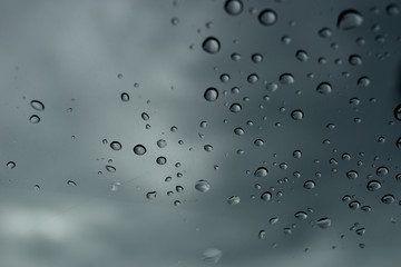 ain drops on glass. black cloud background, view in car
