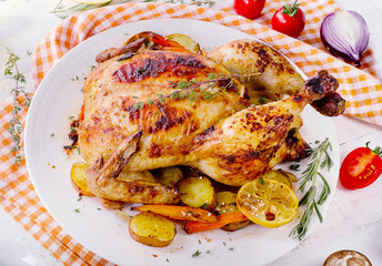 Roasted chicken with vegetables  on white wooden background.
