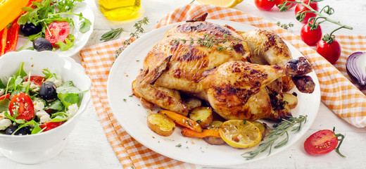 Roasted chicken with vegetables  on a white wooden background.