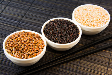 black, red and white unpolished rice on a straw mat