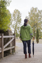 Obraz premium Woman walking with an umbrella in a park with yellow leaves falling from trees