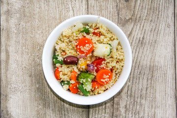 bowl of vegetarian cous cous isolated on a wooden background 