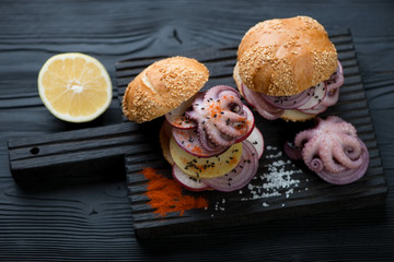 Burgers with galician style octopus over black wooden background