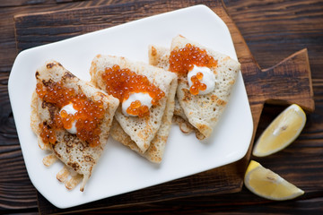Above view of crepes served with sour cream and red caviar
