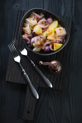 Seafood and potato salad, black wooden background, above view