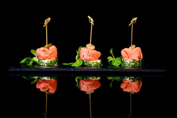 canapes with salmon and capers on black background