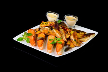 grilled carp and trout with potatoes on black background