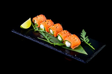 Roll of salmon stuffed with cheese on a black background