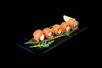 Roll of salmon stuffed with cheese on a black background