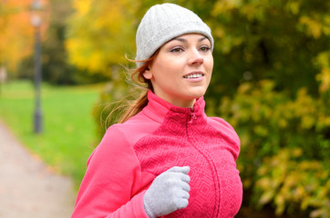 Smiling fit young woman jogging in a park