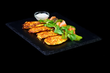 potato pancakes with salmon on black background