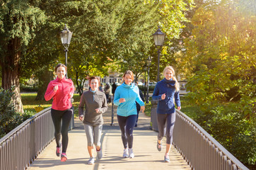 Vier junge Frauen joggen über die Brücke