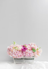 floral basket on the tablecloth in front of the gray wall with c