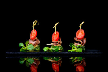 canape beaf tomato bread on black background with reflection