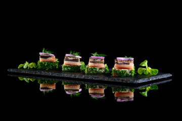 Canapes of herring with bread and cream cheese on black backgrou