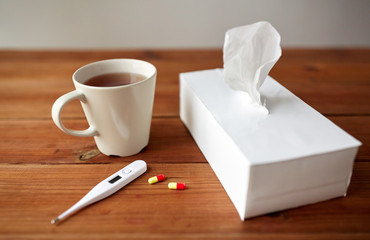 cup of tea, paper wipes and thermometer with pills