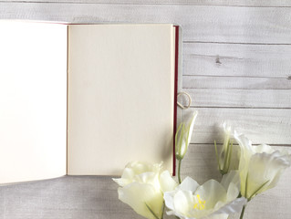 Open notebook or diary, journal with white flowers on grey and white wooden table